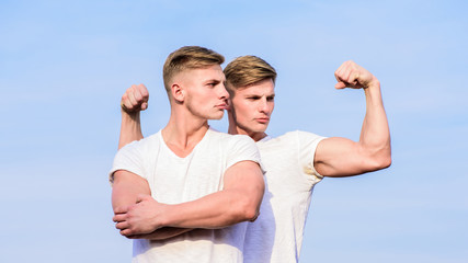 Attractive twins. Handsome strong twins. Men twins muscular brothers sky background. Men strong muscular athlete bodybuilder posing confidently in white shirts. Sport lifestyle and healthy body