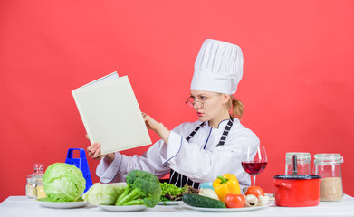 Woman chef cooking healthy food. Girl read book top best culinary recipes. Culinary school concept. Female in hat and apron knows everything about culinary arts. Traditional cuisine. Culinary expert