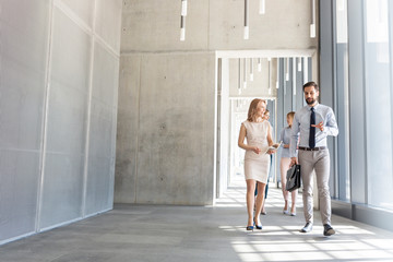 Business colleagues planning while walking in office corridor