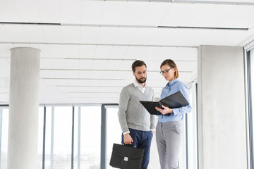 Business colleagues reading file while standing at new office