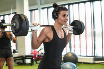 Fototapeta na wymiar Fitness model performing weight lifting exercise at gym