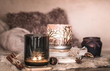 still life home atmosphere in the interior with candles and a book on the background of cozy bedspreads