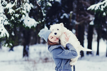 Happy beautiful young woman hugging dog in a winter day