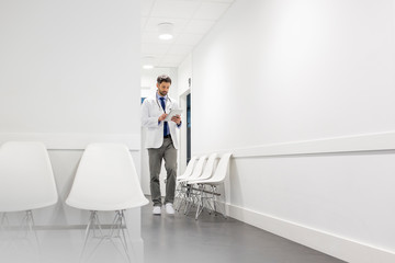 Full length of mid adult doctor using digital tablet at hospital