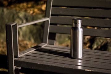 an insulated stainless steel bottle on the bench in the night forest