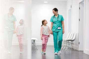 Nurse and girl patient walking in corridor at hospital