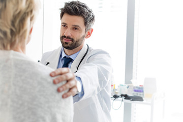 Mid adult doctor consoling mature patient at hospital © MDBPIXS