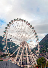 Fototapeta premium ANDORRA LA VELLA, ANDORRA - SEPTEMBER 2014. Ferris wheel turning in Andorra with the Pyrenees alond mountains