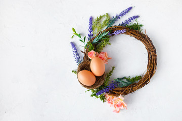 Easter concept. Bright spring flowers, wreath with easter eggs on a light background