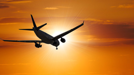 Fototapeta na wymiar Airplane in the sunset sky flight travel transport airline background concept.