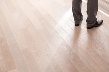 Low section of male realtor standing on hardwood floor at home