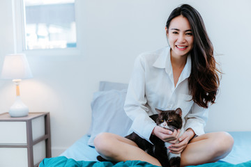 Asian woman playing with cat pet in the morning at holiday hobbie happy lifestyle in bedroom at home