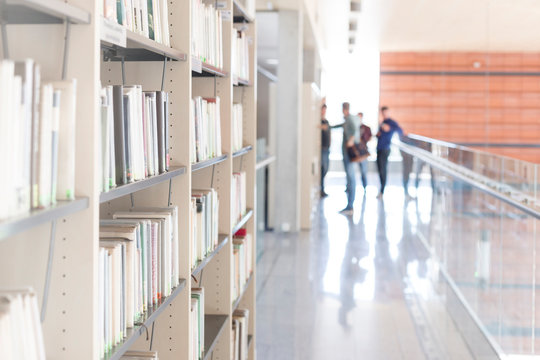 Various books arranged on shelf at corridor in university library