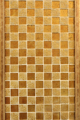 Wall finish with small decorative tiles in gold color