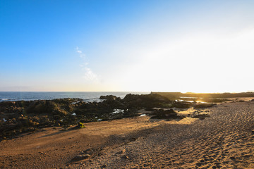 Rocky and sandy beach at sunset, with a blue sky, in Porto, Portugal