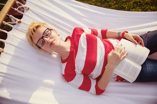 woman reading a book while relaxing on hammock
