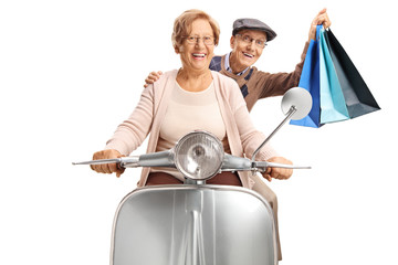 Cheerful senior couple with shopping bags riding a vintage scooter