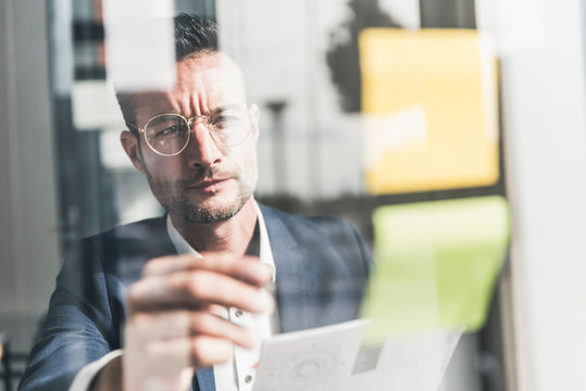 Businessman brainstorming in office, using sticky notes