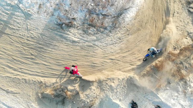 Professional Motocross Motorcycle Rider Drives on the Off-Road Snow Terrain. Aerial View Of Motocross Snow Track. Riders Riding Motobike Race In WInter.
