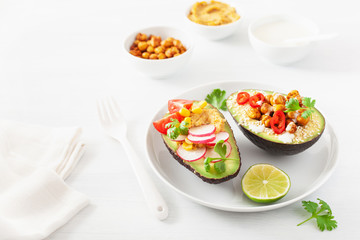 Fototapeta na wymiar avocado boats stuffed with hummus, tomatoes, radish, roasted chickpea