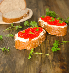 sandwiches with red caviar and a number of greens on a wooden background selective 