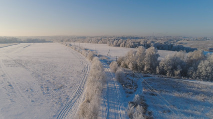 Fototapeta na wymiar aerial view winter landscape countryside road through winter field with forest. winter forest on sunny day. winter in countryside