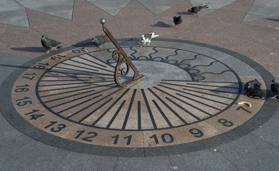 Sundial with pigeons on the waterfront of the city