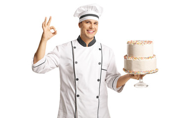 Cheerful male cook holding a two layer cake and gesturing with fingers