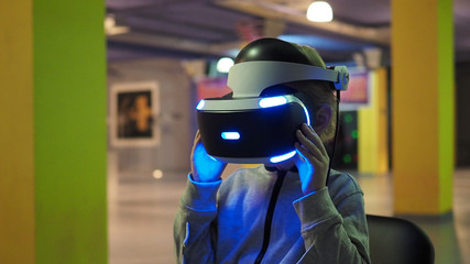 child sits in a large game room and looks at the glasses for virtual reality