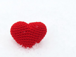 Red knitted Valentines heart in the snow. Symbol of romantic love with snowflake, concept of blood donation, health care