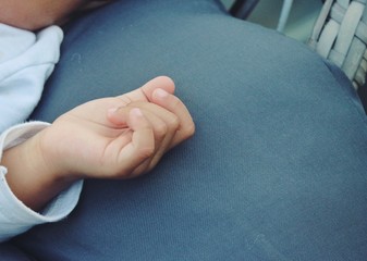 Hand of sleeping child on blue sofa background.