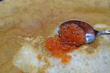 Delicious fresh pancakes and red caviar in a spoon.