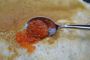Delicious fresh pancakes and red caviar in a spoon.