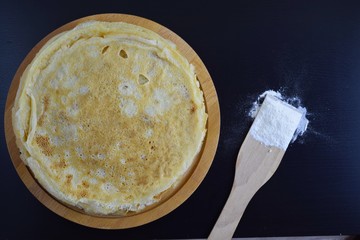 Delicious pancakes and flour on black background.