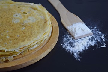 Delicious pancakes and flour on black background.