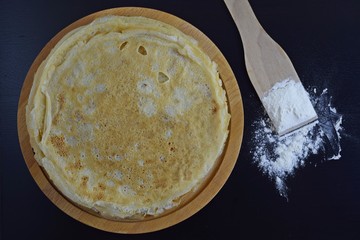 Delicious pancakes and flour on black background.