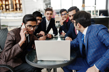 Obraz premium Group of six indian business man in suits sitting at office on cafe and looking at laptop.
