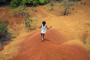 NOSY SAKATIA ISLAND, MADAGASCAR - OCTOBER 16,2018: Malagasy girl runs down the dunes among the rainforest