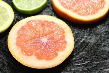 Grapefruitscheiben und Limettenscheiben auf schwarzem Holzuntergrund