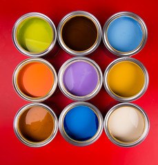 Collection of colored paints cans, red background