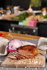 A piece of cooked meat and slices on a wooden plate