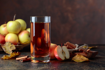 Glass of apple juice or cider with juicy apples and cinnamon sticks.