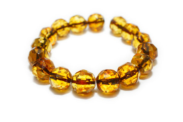 Amber bracelet made from round beads with hexagonal amber on a white background. Beads from a natural mineral hardened ancient resin. Jewelry from a sunstone. Jewelry store advertising. Crystals