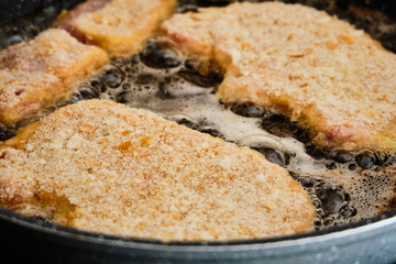 Preparing schnitzel on frying pan