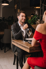 handsome boyfriend looking and smiling at girlfriend in red dress