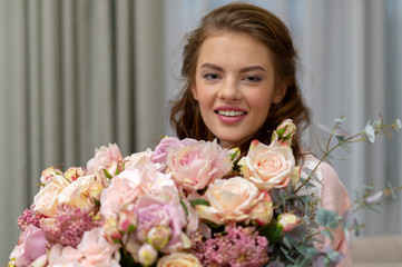 Attractive woman with bouquet of hundreds of flowers is spending time at home.