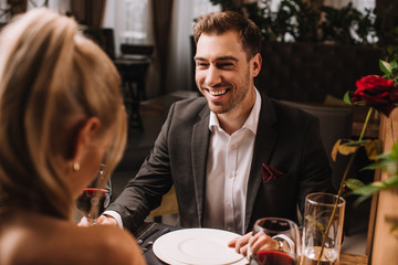 handsome man laughing in restaurant while looking at woman