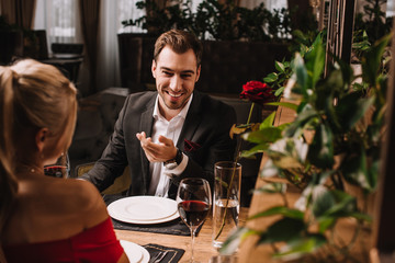 handsome man laughing while looking at girl in restaurant
