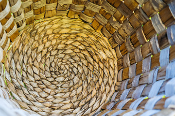 The bottom of a wicker basket of natural materials. By spiral.