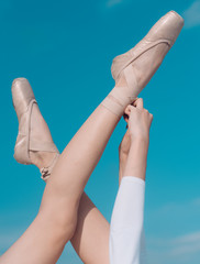 Touching the sky. Pointe shoes worn by ballet dancer. Ballet slippers. Ballerina shoes. Ballerina legs in ballet shoes. Female feet in pointe shoes. Classic dance style. Concert dance performance © Volodymyr